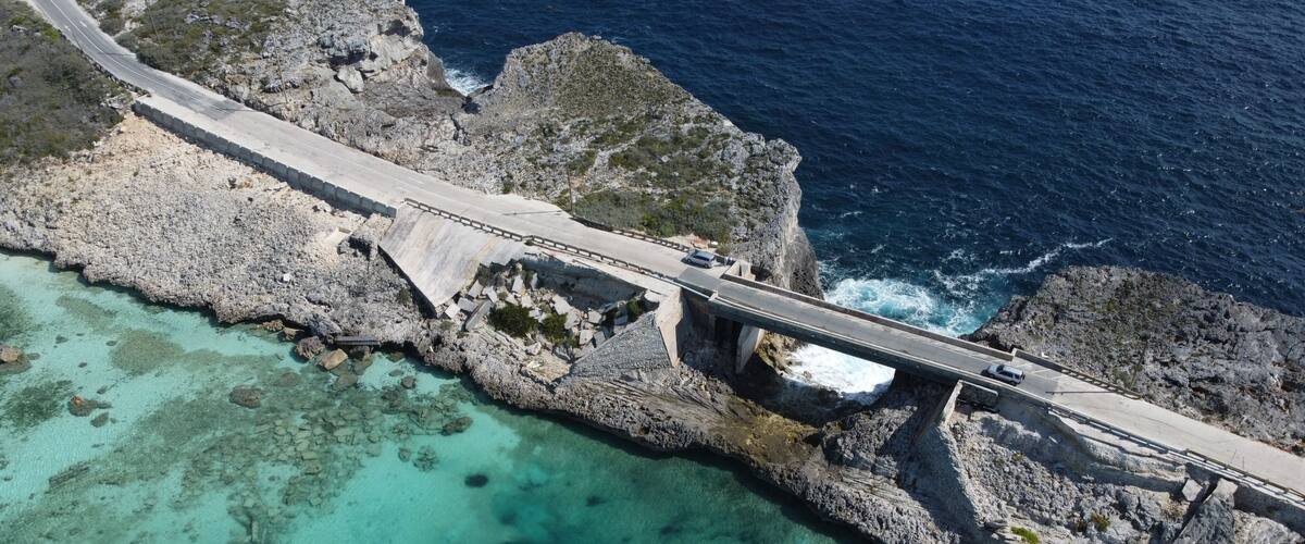 A coastal road bridge with clear turquoise waters and rocky cliffs.