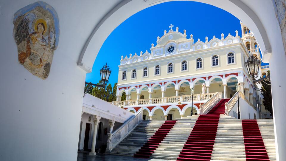 A grand staircase leading to a white building with red accents and a blue sky.
