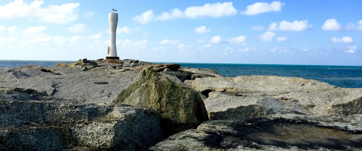A lighthouse on rocky terrain with the ocean in the background.