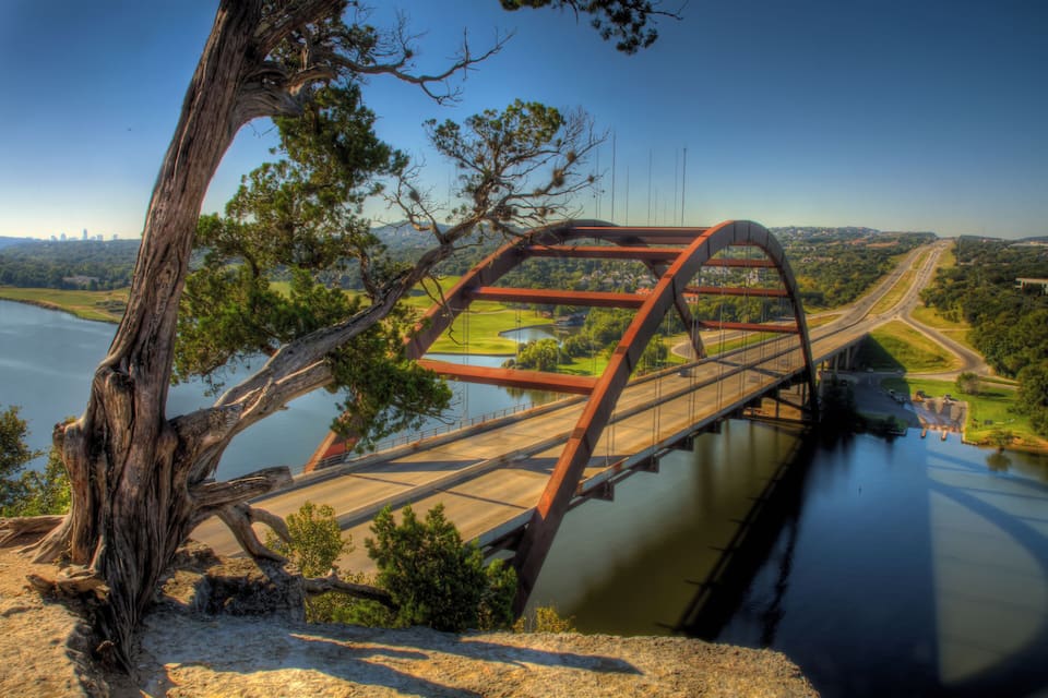 Un puente sobre un río, con un árbol a la izquierda.