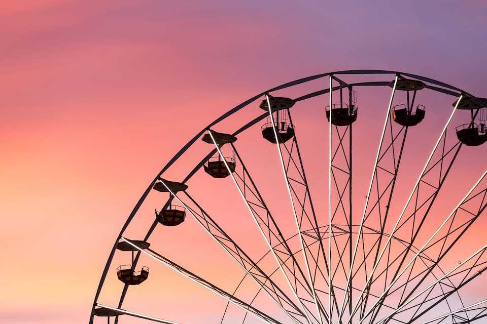 A large Ferris wheel against a sunset sky.
