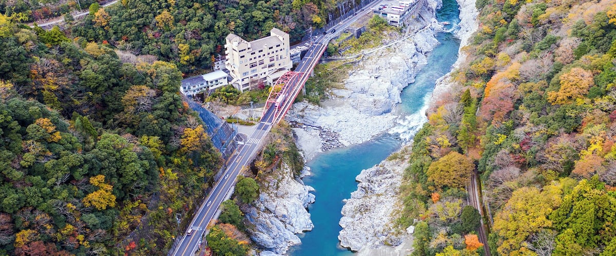 A coastal road with a bridge, a building, and a rocky shoreline.