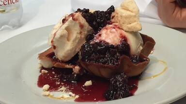 A dessert plate with ice cream, berries, and crumbled cheese.