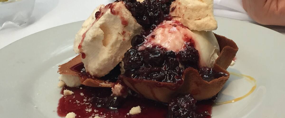 A dessert plate with ice cream, berries, and crumbled cheese.