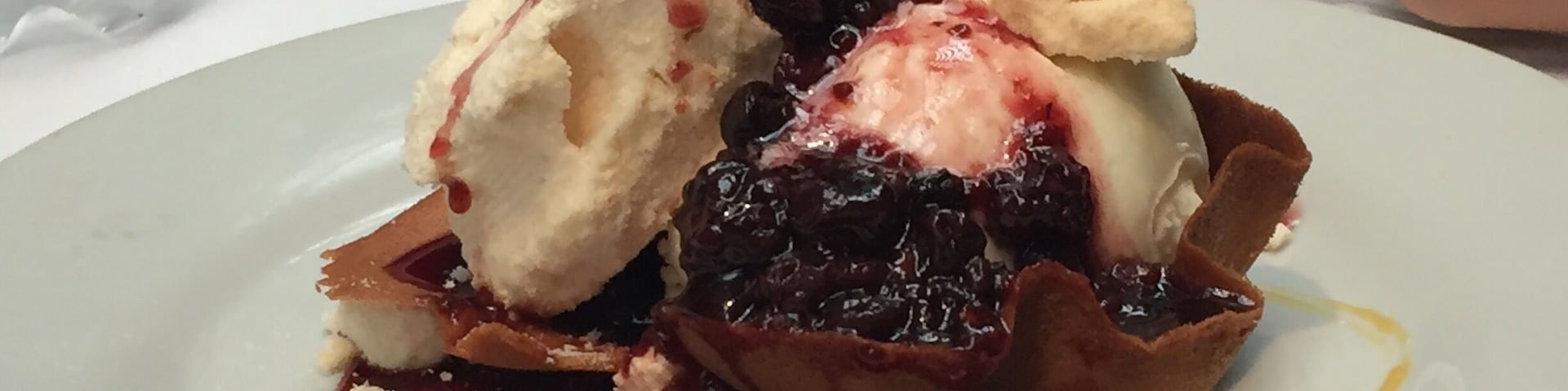 A dessert plate with ice cream, berries, and crumbled cheese.