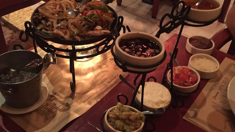 A dining table with various dishes, including a pot of soup, bowls of rice, and a plate of noodles.