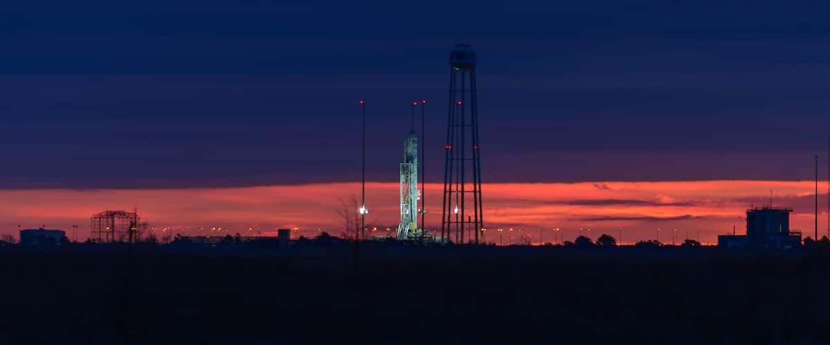 A rocket launch tower at dusk with a sunset sky.