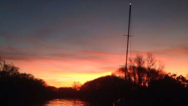A sunset over a calm river with a boat in the foreground.
