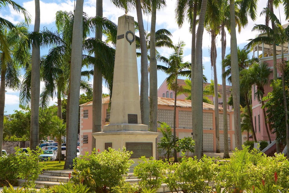 Un monument alt envoltat de palmeres i un edifici rosa amb teulada de palla.