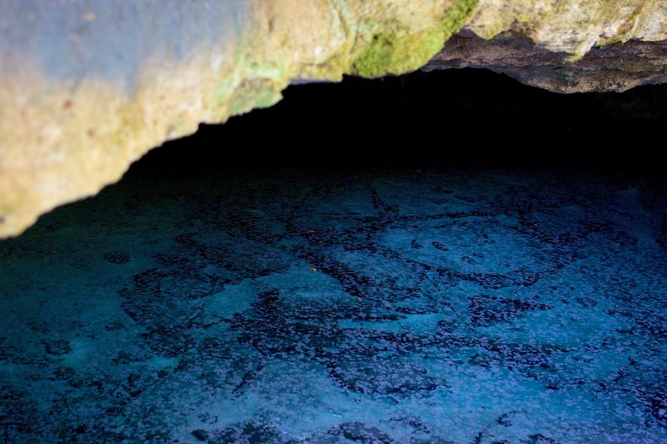 Interior d'una cova amb aigua blava i sostre rocos.
