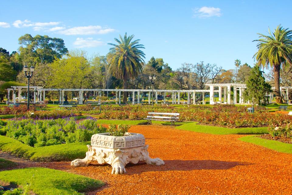 Un parc amb un kiosc blanc, palmeres i una estàtua.