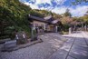 A traditional Japanese building surrounded by trees and a gravel path.