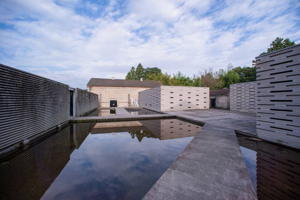 A modern building with a reflective pool and a clear sky.