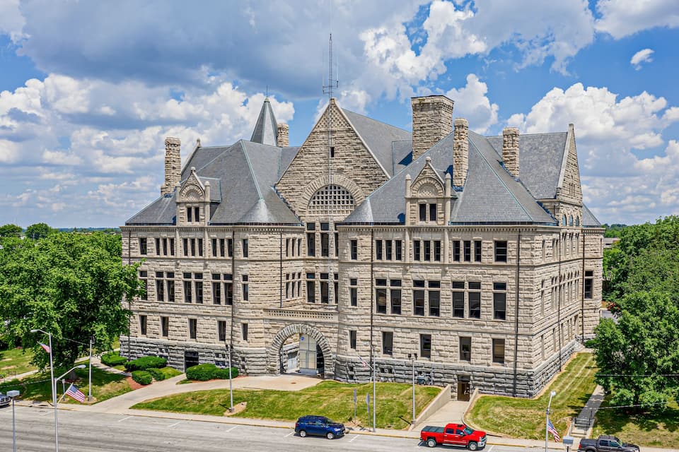 A large stone building with multiple chimneys and a flag.
