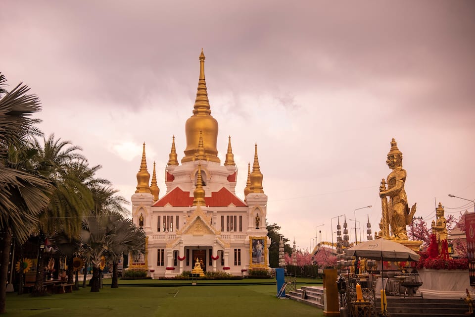 A white temple with golden spires and a golden statue in front.