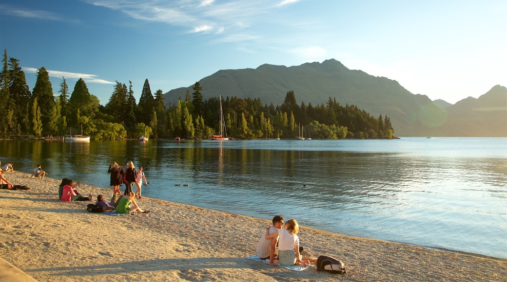 Queenstown Beach som inkluderar berg, en solnedgång och en stenstrand