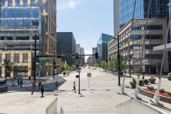 Une rue de la ville, avec des bâtiments modernes, des piétons et un ciel dégagé.