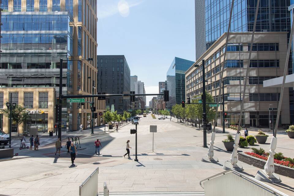 Une rue de la ville, avec des bâtiments modernes, des piétons et un ciel dégagé.