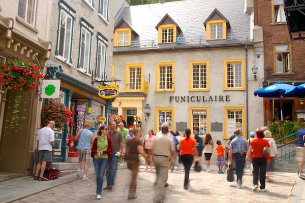 Eine belebte Straße mit Spaziergängern, ein Gebäude mit der Aufschrift „FUNICULAIRE“ und Geschäfte mit farbenfrohen Schildern.