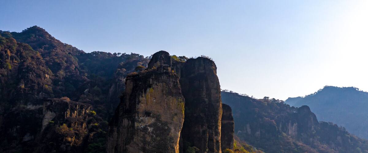 A mountainous landscape with prominent rock formations and dense vegetation.