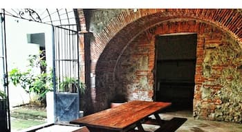 A rustic outdoor setting with a wooden picnic table and benches, an arched brick wall, and a metal gate.