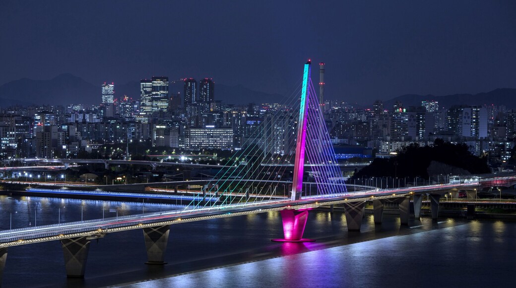 Gangseo-gu, Seoul, South Korea - October 26, 2022: High angle and night view of World Cup Bridge with colorful illumination on Han River against Olympic Boulevard and apartments