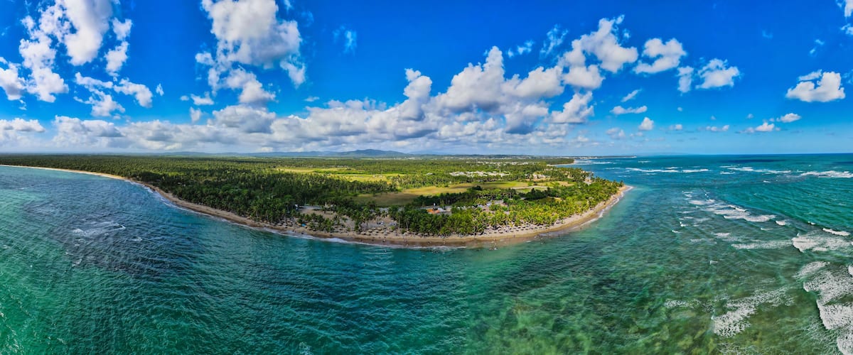 A tropical island with clear turquoise waters, a sandy beach, and lush greenery.