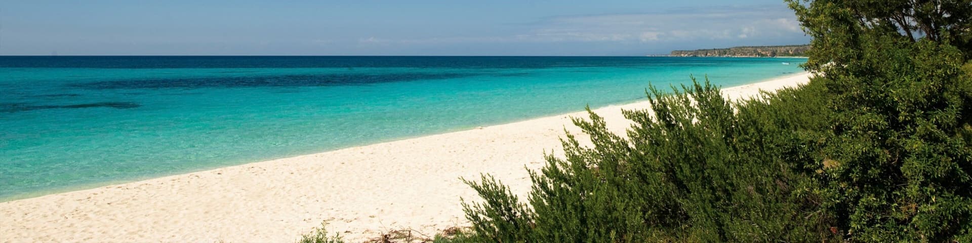 A beach with clear turquoise water and white sand.