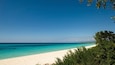 A beach with clear turquoise water and white sand.