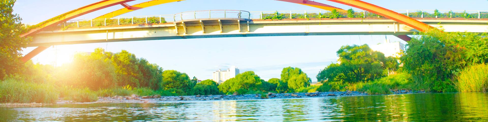 Steel bridge over river with sunset in countryside.