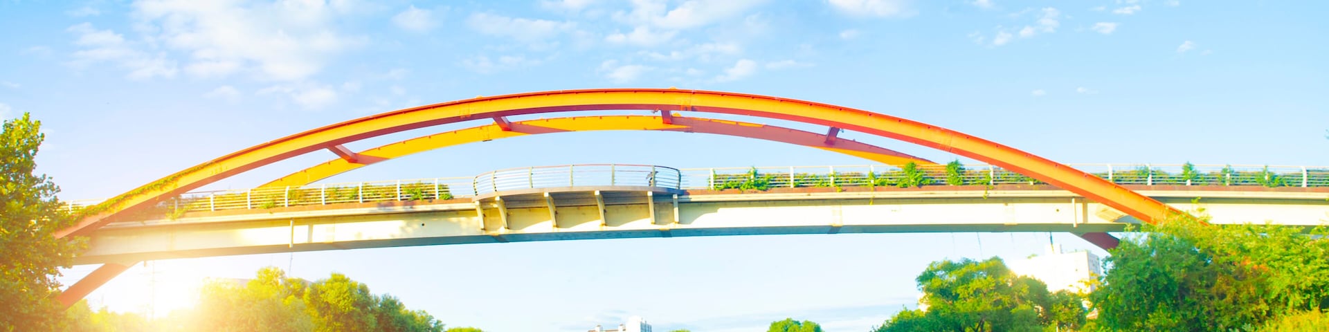 Steel bridge over river with sunset in countryside.