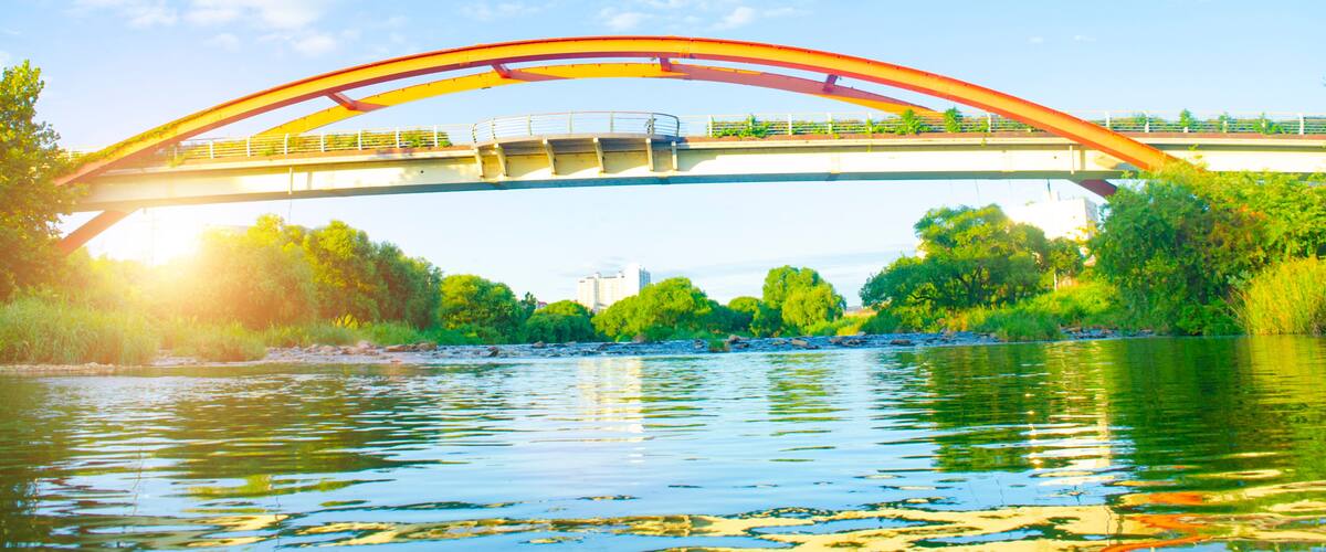 A bridge over a river with greenery on both sides.