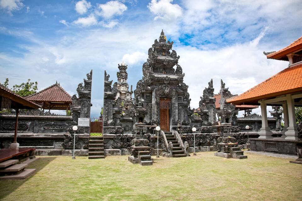 Un tempio tradizionale balinese con elaborate sculture, un santuario centrale e un cortile circostante.