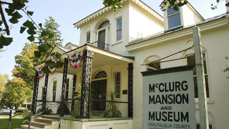 The McClurg Mansion and Museum with a white facade, a front porch, and a signboard.