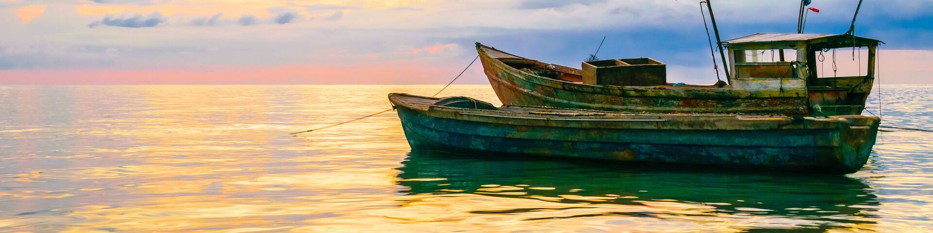 Old fishing boats floating near the coastline at sunset in Westmoreland, Jamaica