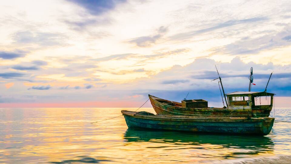 A boat on calm waters with a sunset sky.