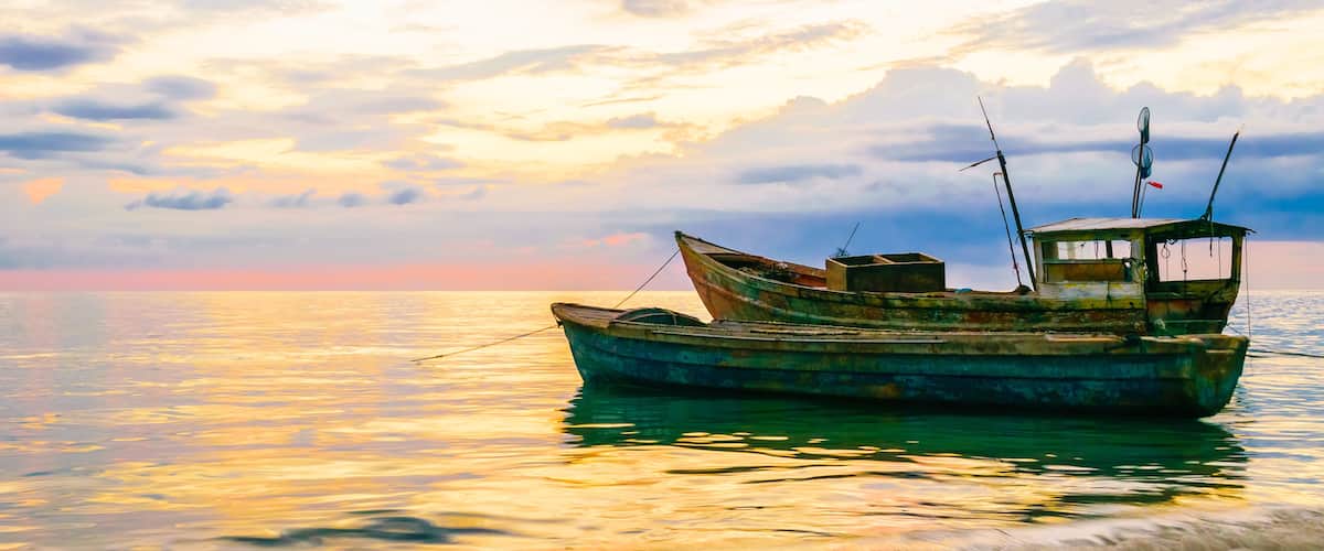 A boat on calm waters with a sunset sky.