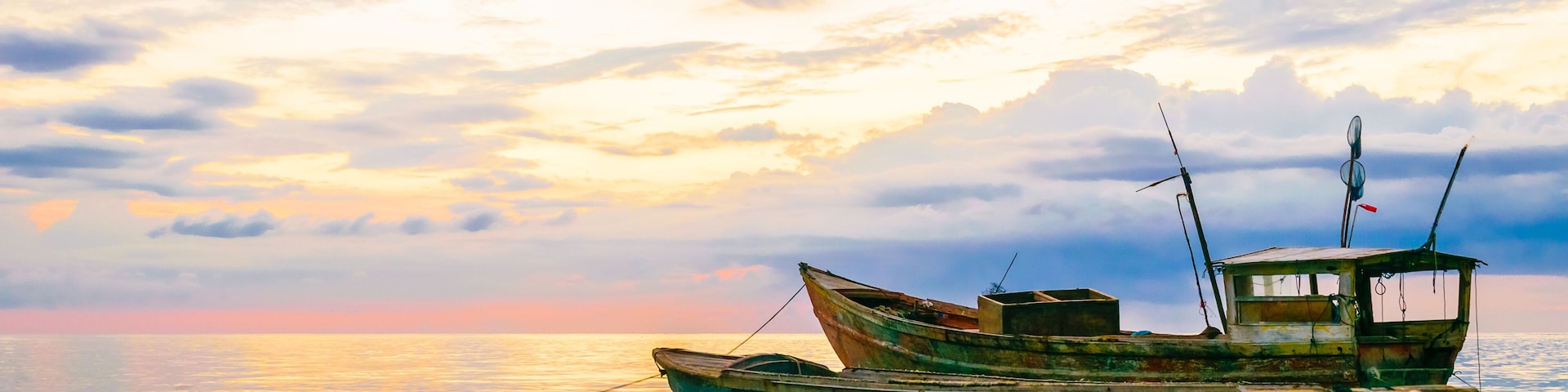 A boat on calm waters with a sunset sky.