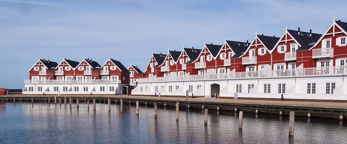A row of red and white houses by a calm waterfront.