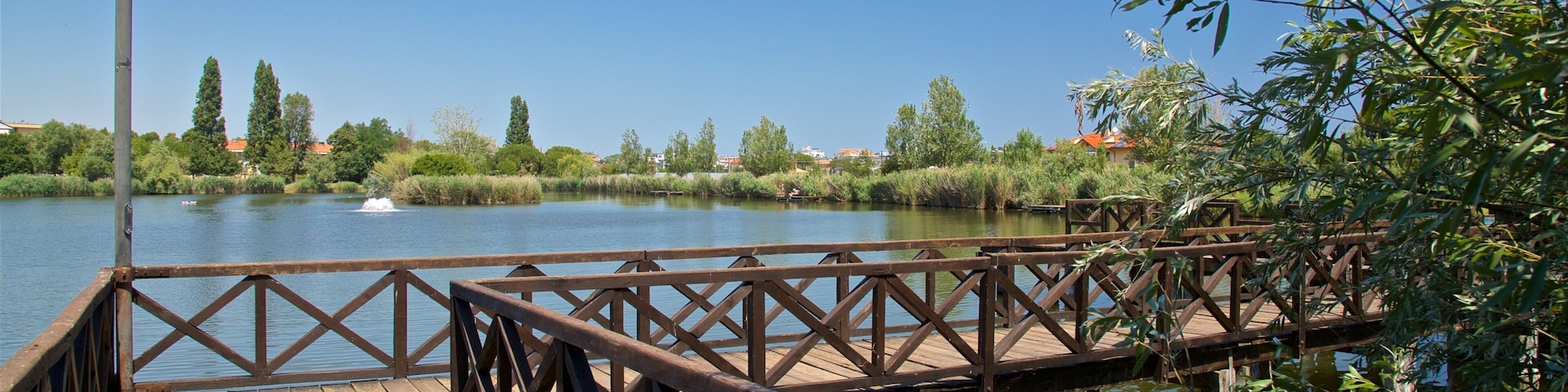 A wooden bridge over a calm river with a lamp post on the left.