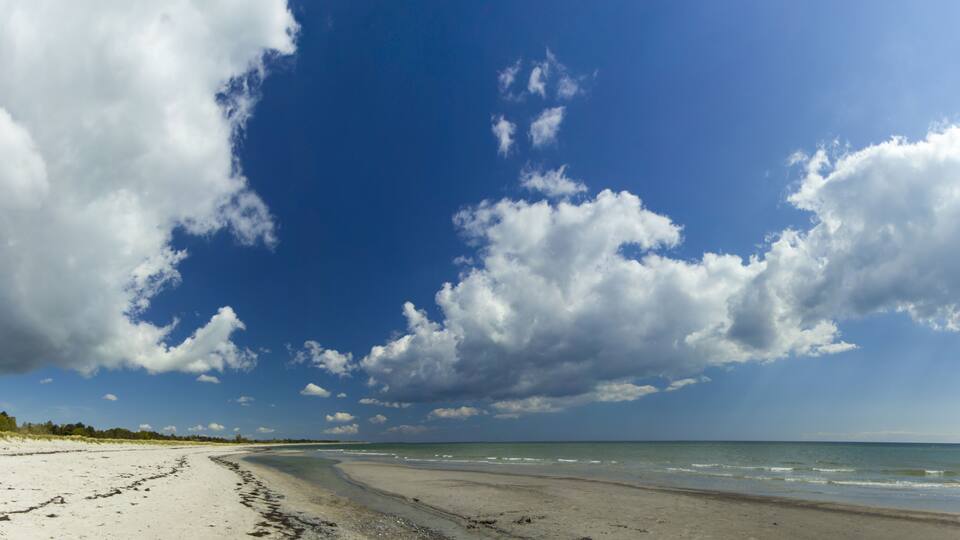 A beach with a clear sky and large clouds.