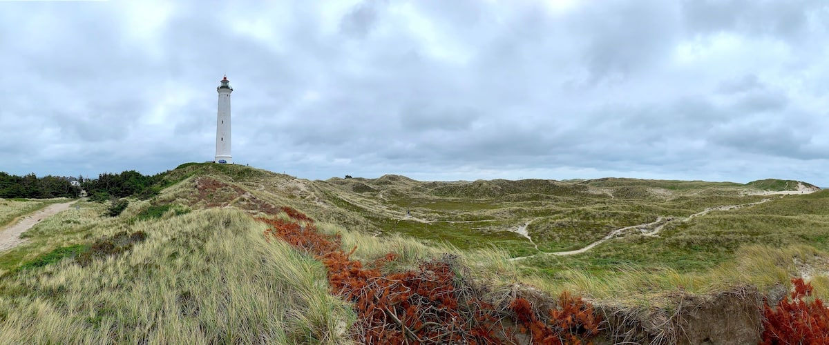 A lighthouse on a grassy hill with winding paths.
