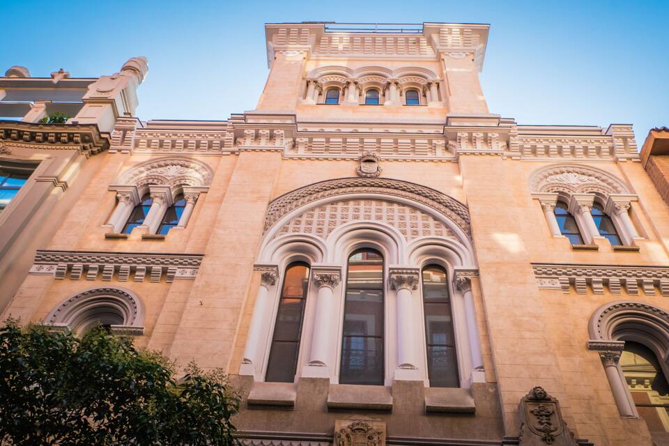 Edifício histórico com arquitetura ornamentada, incluindo janelas em arco e detalhada pedraria.