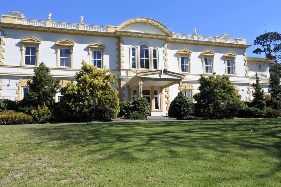 A large, historic building with a symmetrical facade, large windows, and a central entrance with a portico.