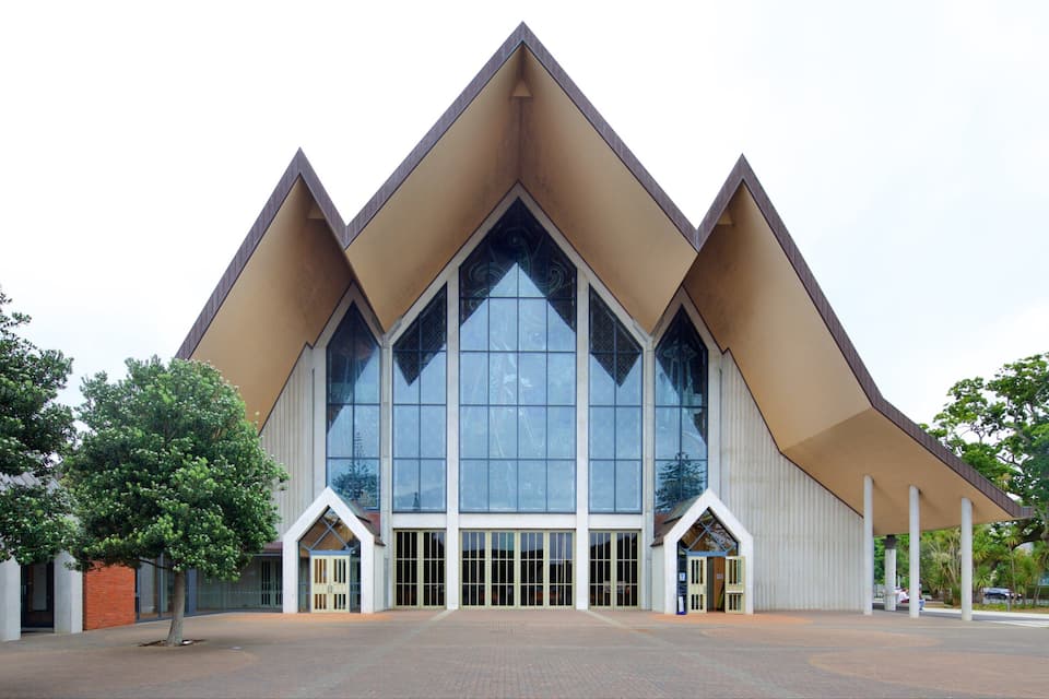 A modern building with a unique triangular roof design and large glass windows.