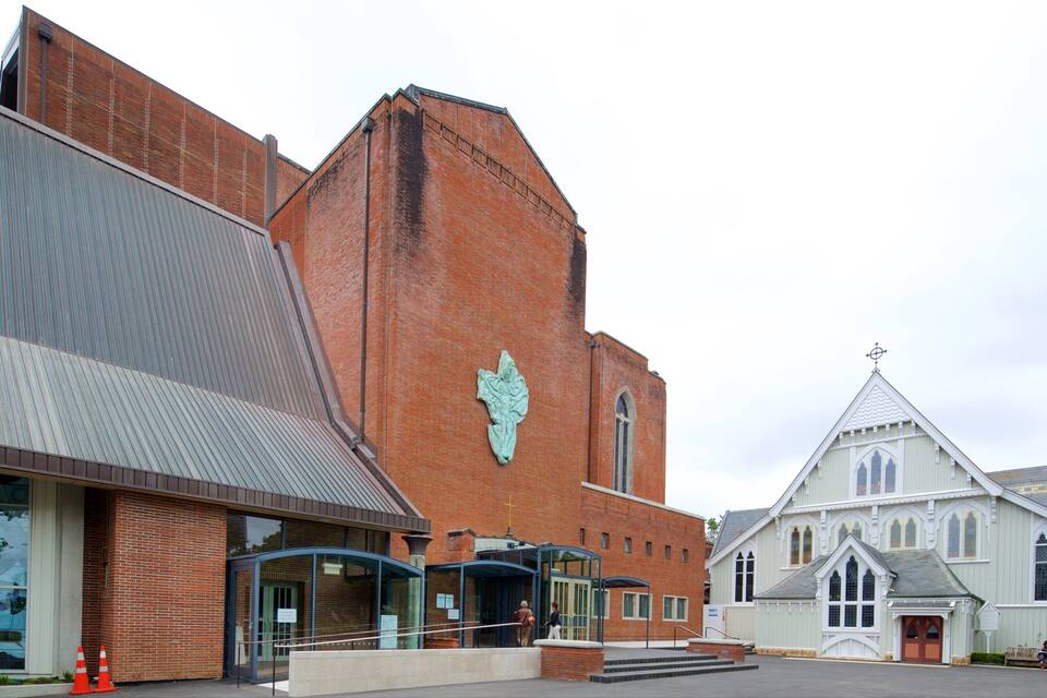 A church with a large steeple and a modern building with a metal roof.