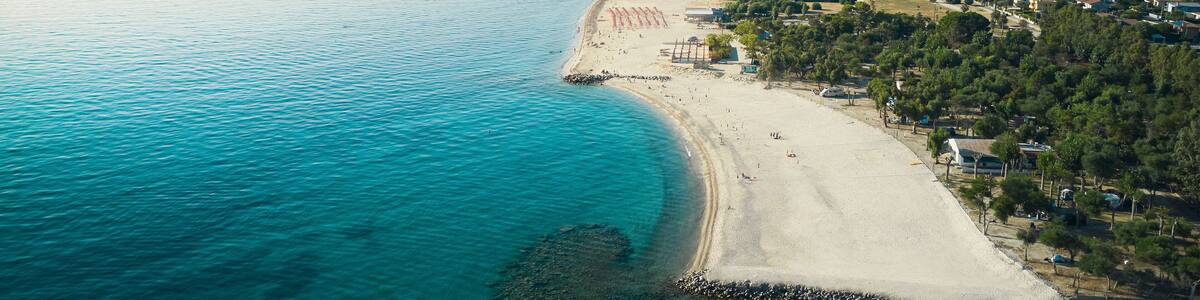 Aerial view of a beautiful coastline with sandy beach, turquoise sea, lidos and lush parks in Isca sullo Ionio, Calabria, Italy.