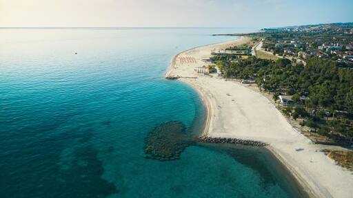 Aerial view of a beautiful coastline with sandy beach, turquoise sea, lidos and lush parks in Isca sullo Ionio, Calabria, Italy.