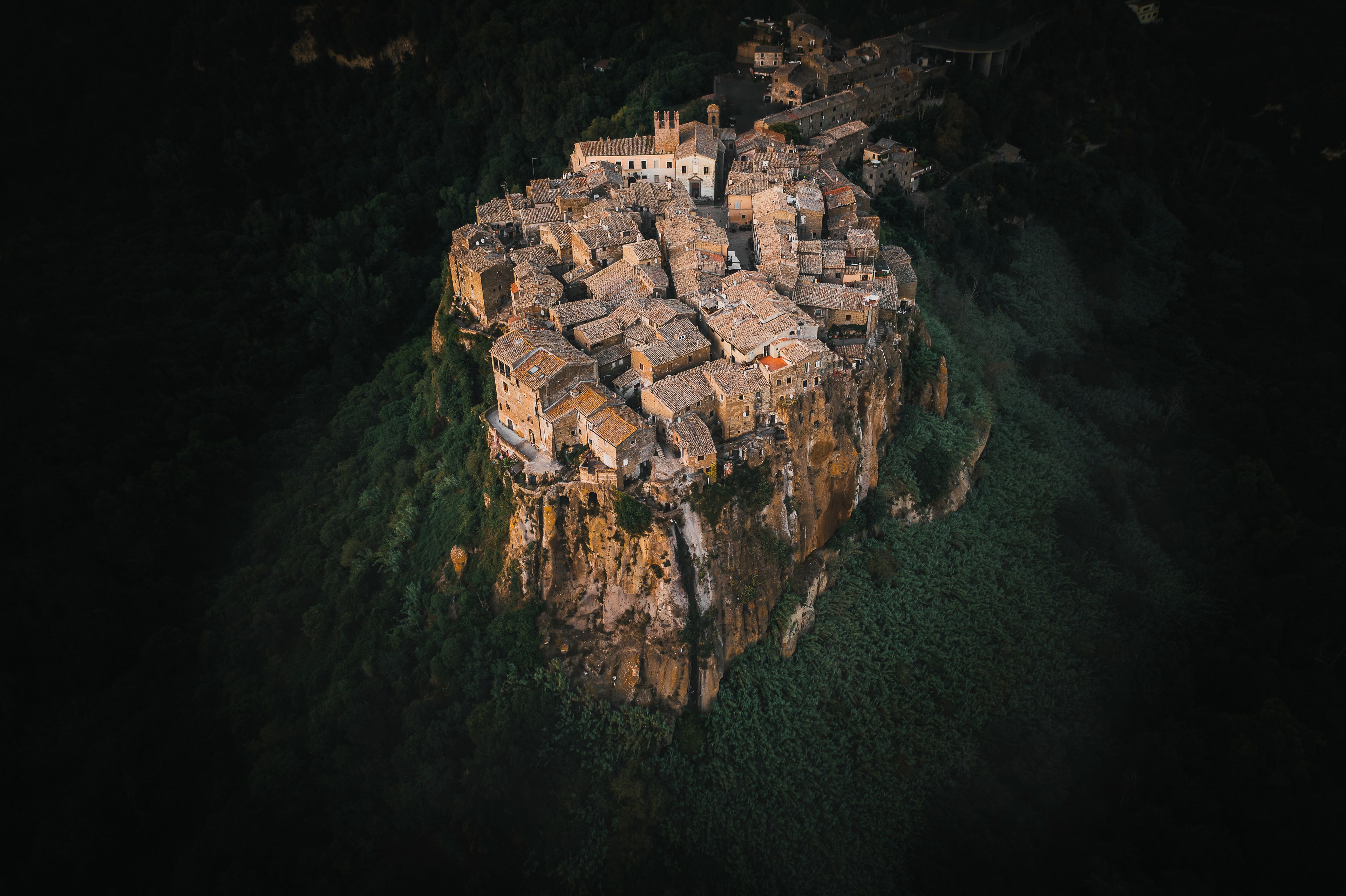 Uma vila medieval empoleirada em um penhasco com edifícios de telhados em terracota.