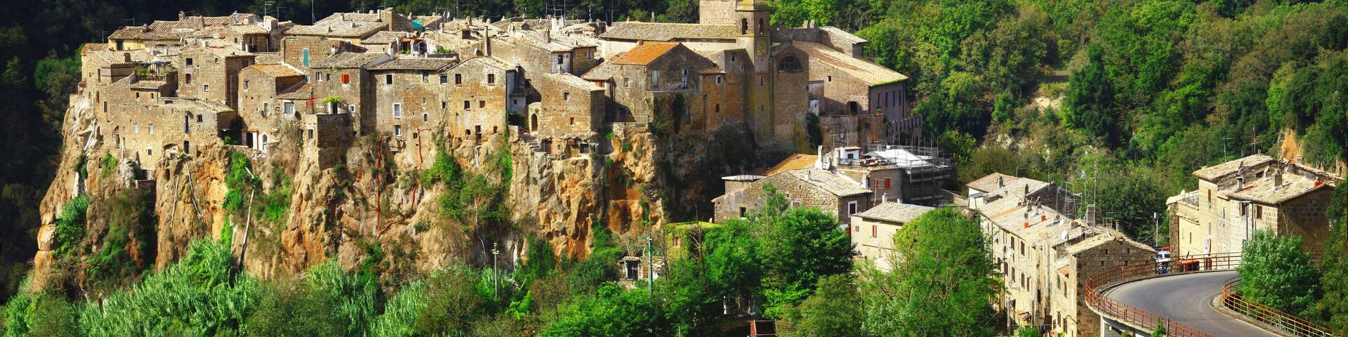 A historic fortified town perched on a cliff, surrounded by lush greenery.